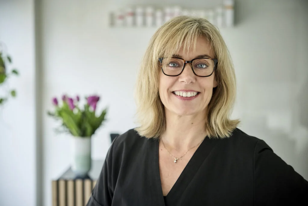 Kvinde med briller smiler indendørs